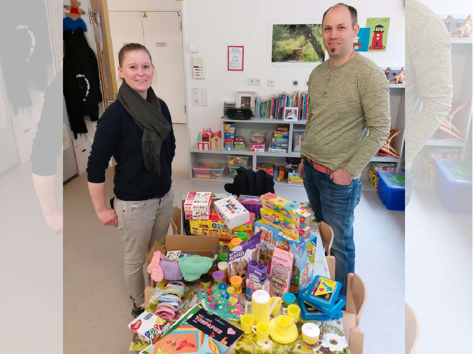 Frau und Herr Bienzle stehen im Spielzimmer neben einem Tisch, auf dem viele bunte Spielsachen liegen