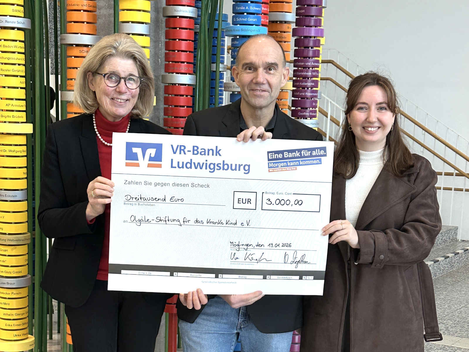 Uwe Kämpfer zwischen Mara Rüger und Dr. Stefanie Schuster, halten den symbolischen Spendenscheck