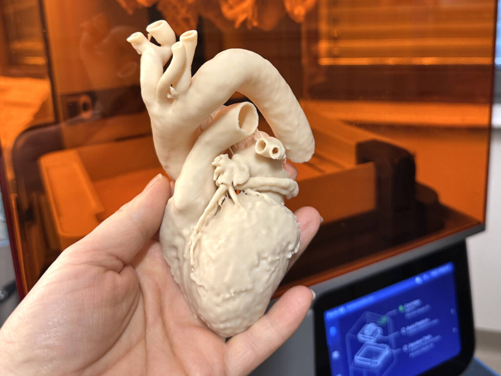 Eine Hand hält ein 3D-Herz aus beigem Material