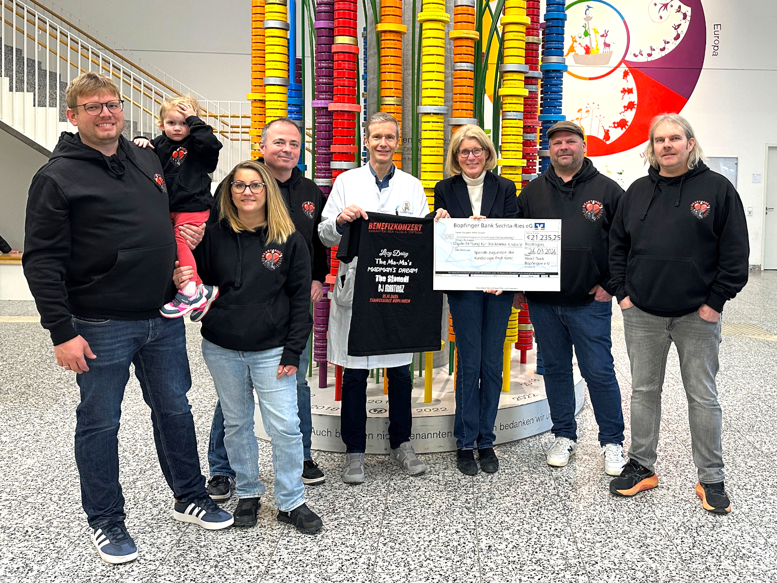 5 Personen des Vorstandsteams von Heard Rock Bopfingen in schwarzen Vereins-Hoodies. In deren Mitte Prof. Dr. Gunter Kerst und Dr. Stefanie Schuster mit dem symbolischen Spendenscheck vor der Spendensäule